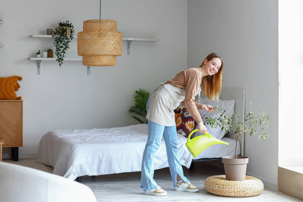 Giovane donna annaffiamento pianta d'appartamento in camera da letto - Foto, immagini