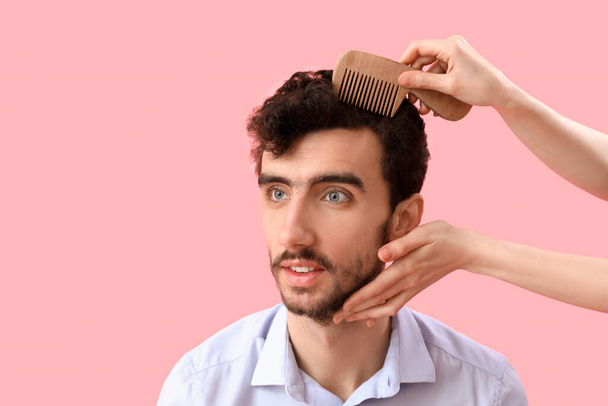 Žena kadeřnice česání vlasů mladého muže na růžovém pozadí, detailní záběr - Fotografie, Obrázek