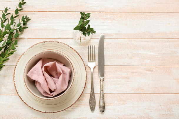 Bella tavola apparecchiata con vaso di rami di piante e tovagliolo su sfondo di legno rosa - Foto, immagini