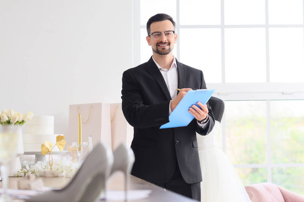 Male wedding planner working with clipboard in office - Photo, Image