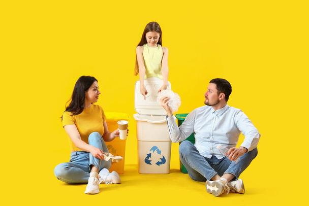 Perhe lajittelu roskat roskakorit keltaisella pohjalla - Valokuva, kuva