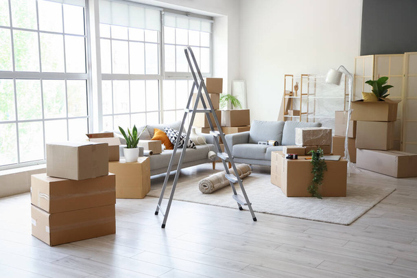 Sofás con escaleras y cajas de cartón en la sala de estar en el día en movimiento - Foto, imagen