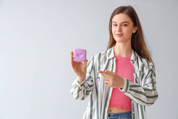 Young woman pointing at box of tampons on light background - Photo, Image