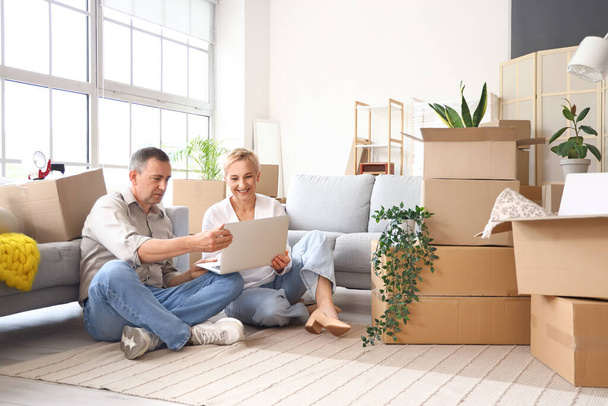 Mature couple using laptop in room on moving day - Photo, Image