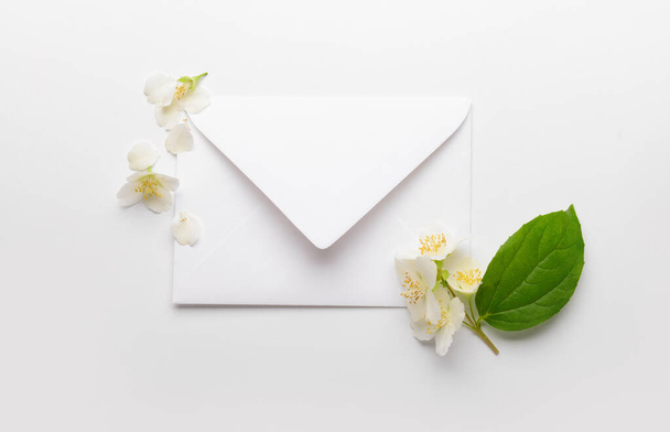 Composition with envelope and beautiful jasmine flowers on light background - Photo, Image