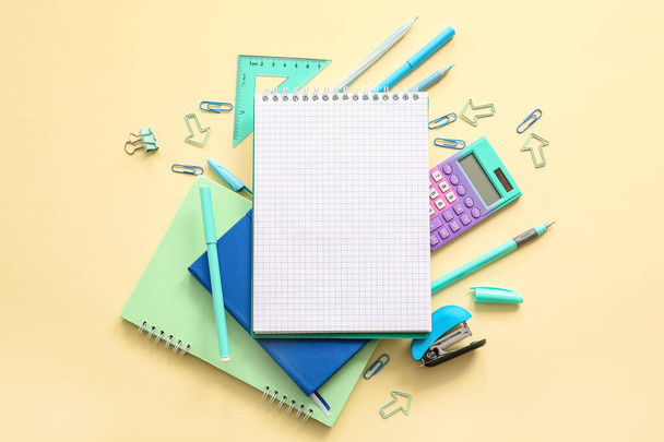 Composición con cuaderno en blanco y diferentes artículos de papelería escolar sobre fondo beige - Foto, imagen