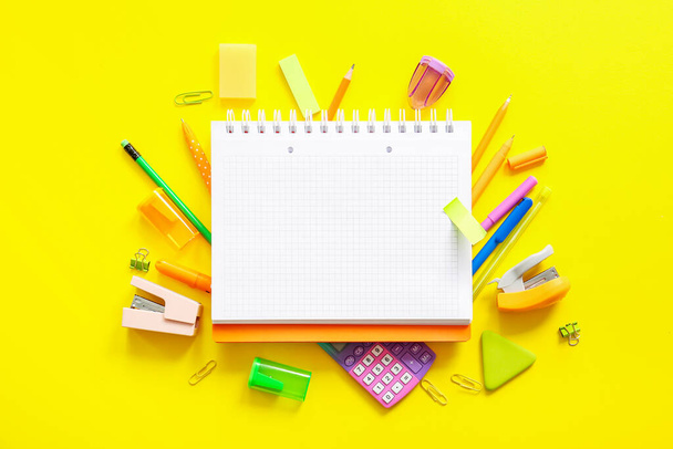 Composition with blank notebook and school stationery on yellow background - Photo, Image