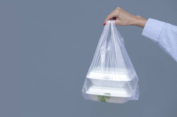 Naisen kädet pitelee PVC muovipussi noutovaahto lounaslaatikot. Kertakäyttöiset elintarvikepakkaukset, luovutuskonsepti. - Valokuva, kuva