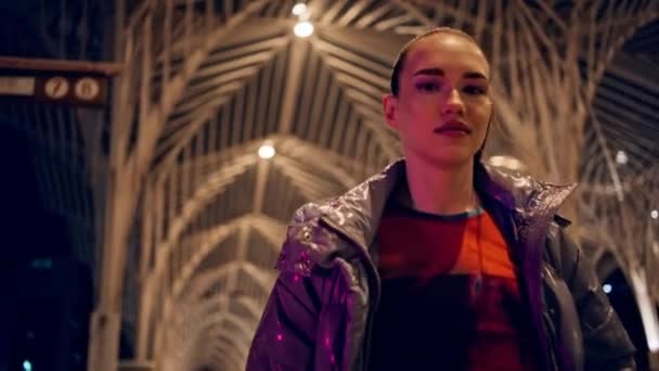 Happy cool teenage girl spinning around walking gothic city night closeup. Confident stylish woman posing camera wear trendy jacket late evening. Carefree attractive brunette having fun feeling free - Footage, Video