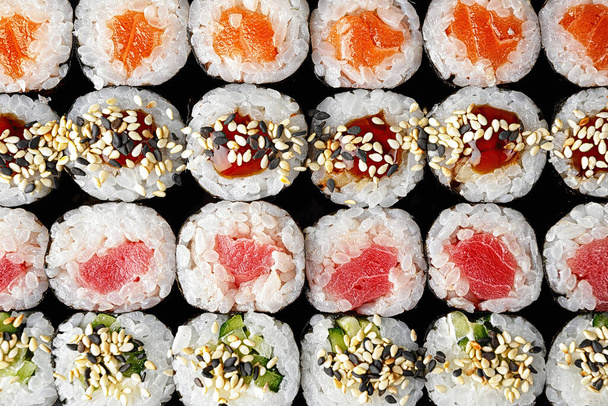 Набор суши-рулонов в ассортименте на черном фоне - Фото, изображение