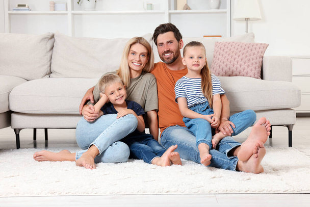 Portrait of happy family with children on soft rug at home - Фото, изображение