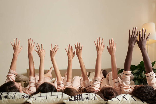 Grupa młodych kobiet leżących na podłodze i podnoszących ręce do góry - Zdjęcie, obraz