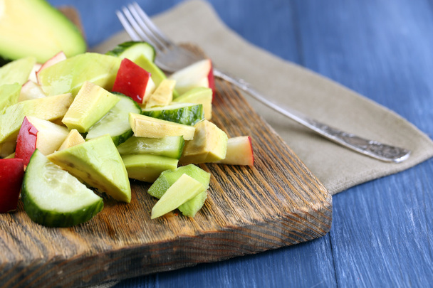 Sliced avocado and apple on cutting board on wooden background - Fotografie, Obrázek