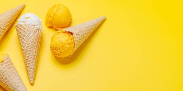 Surtido de sabores de helado en deliciosos conos de gofres, un regalo para todos los papilas gustativas. Sobre fondo amarillo con espacio de copia - Foto, imagen