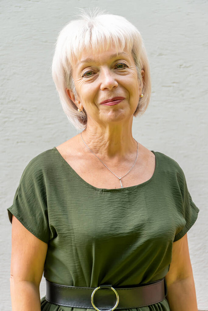 портрет улыбающейся пожилой женщины 60-65 лет с седыми волосами на светлом фоне, концепция: стильные пенсионеры модельного вида, активная жизнь, - Фото, изображение