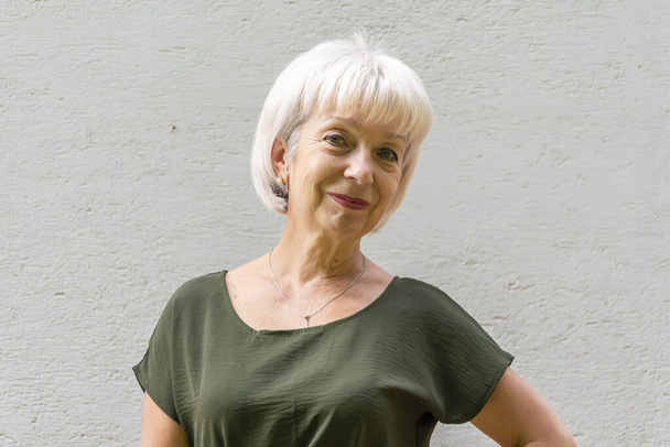 retrato de una anciana sonriente de 60-65 años de edad con el pelo gris sobre un fondo claro, Concepto: pensionistas con estilo de apariencia modelo, vida activa, - Foto, Imagen