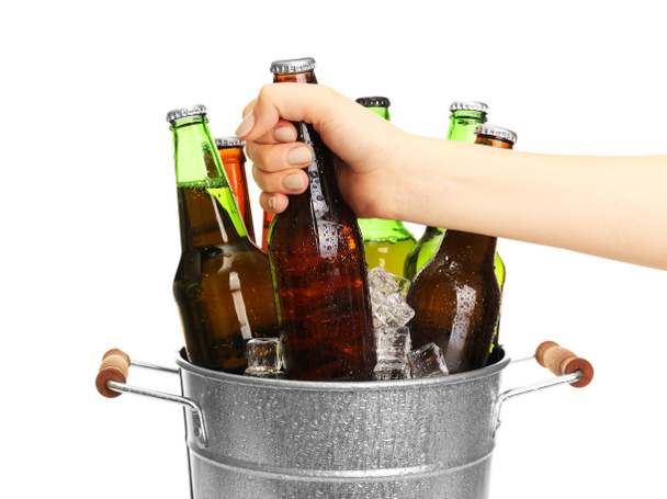 Female hand taking glass bottle of beer from metal bucket isolated on white - Photo, Image