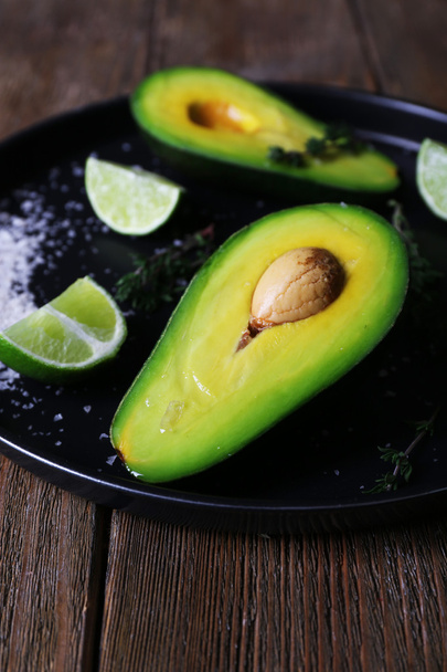 Sliced avocado with lime and herb on metal plate on wooden table, closeup - Foto, immagini