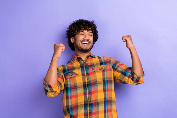 Photo of overjoyed positive man closed eyes raise fists accomplishment luck isolated on violet color background. - Photo, image