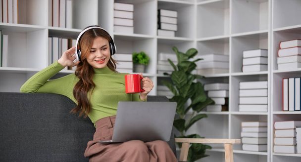 Thuis levensstijl vrouw ontspannen liggend in de woonkamer. Happy girl luisteren muziek op laptop voor wellness en gezondheid in het weekend vakantie. - Foto, afbeelding