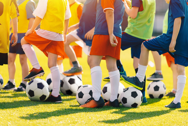 Antrenman sınıfında futbol topu olan bir grup çocuk. Küçük okul çocukları için açık hava futbol antrenmanı. Erkekler ve kızlar yaz günü spor antrenmanında eğleniyorlar. - Fotoğraf, Görsel