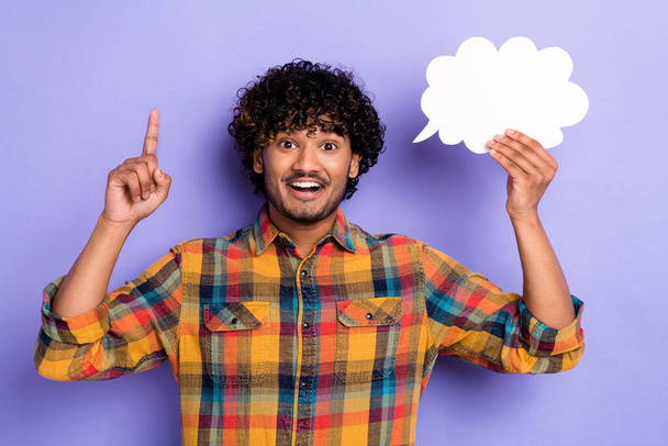Portrait of young student indian man finger direct up eureka holding bubble figure cloud invention isolated on violet color background. - 写真・画像