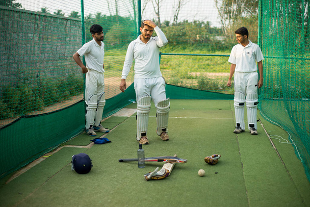 Игроки в крикет готовы попрактиковаться после отдыха, игроки расслабляются после сессии. - Фото, изображение