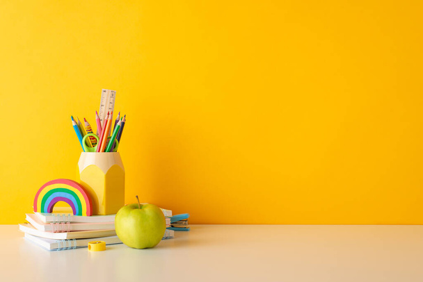 小さな学習者に最適な,テキストや広告の配置のために設計された黄色い隔離された背景に,陽気な学校用品,ペンホルダー,リンゴのこの側面ビューのスナップショットで学ぶことの喜びを受け入れます - 写真・画像