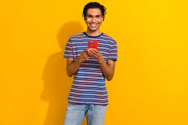 Photo of glad cheerful man popular blogger wear stylish clothes use modern iphone sumsung isolated on yellow color background. - Foto, immagini