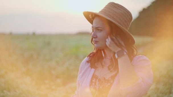 Close-up of a woman listening to music and dancing in a field at sunset. A happy smiling girl with a sense of freedom moves to the rhythm of music in nature. High quality 4k footage - Footage, Video