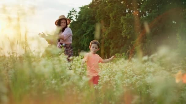 Happy smiling mother and son dancing together in field at sunset. Smiles of the family time spent together in the movements of the dance. High quality 4k footage - Filmati, video