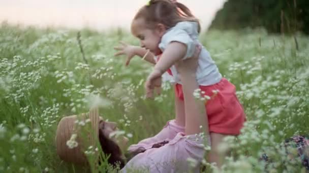 Bir anne ve kızın çimlerin üzerinde sarılıp oynaştığı komik bir video. Bir kızın mutluluğu kavramı. Yüksek kalite 4k görüntü - Video, Çekim