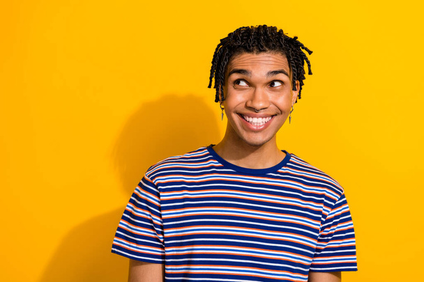 Photo of cheerful positive guy wear trendy striped clothes looking empty space interesting offer isolated on yellow color background. - Fotografie, Obrázek