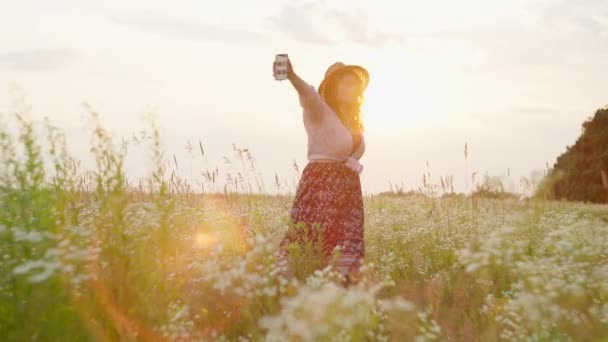 Красивая романтическая девушка в платье танцует в поле на закате. Движения к ритму музыки мягкие и ритмичные. Понятие свободы союза с природой. Высококачественные 4k кадры - Кадры, видео