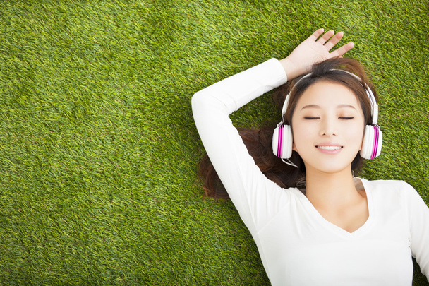 Mujer relajada escuchando la música con auriculares acostados en th
 - Foto, imagen