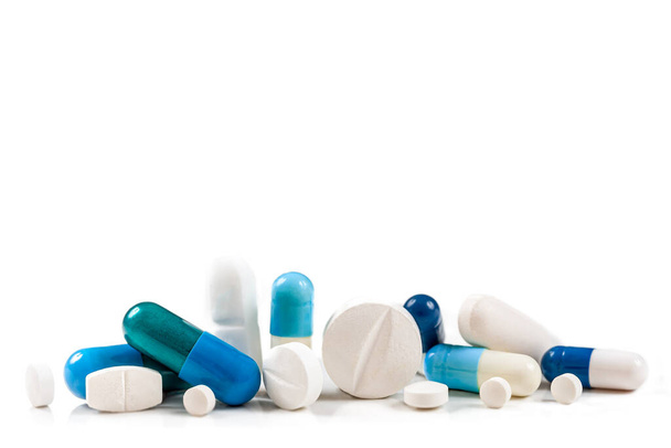 Blaue und weiße Kapseln und Tabletten auf weißem Hintergrund. - Foto, Bild