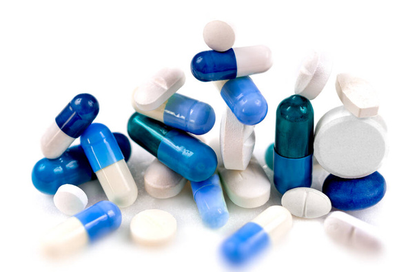 Blue and white capsules and tablets on a white background. - Photo, Image