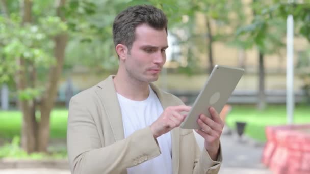 Hombre joven casual molesto por la pérdida en la tableta al aire libre - Metraje, vídeo