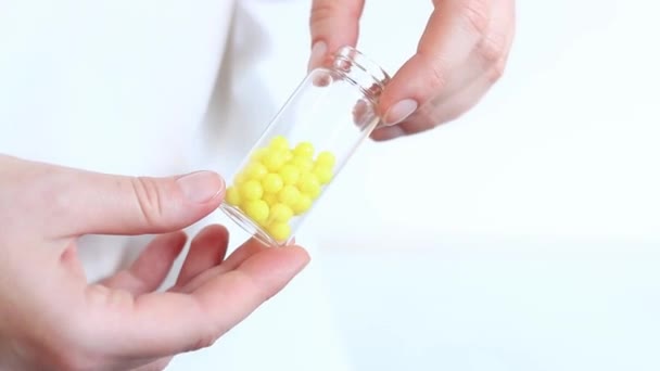 Žluté pilulky ve skleněné lahvičce. Vitamíny v ženských rukou na lehkém pozadí. Vitamíny a doplňky stravy detailní záběr. Vitamin C, kyselina askorbová - Záběry, video