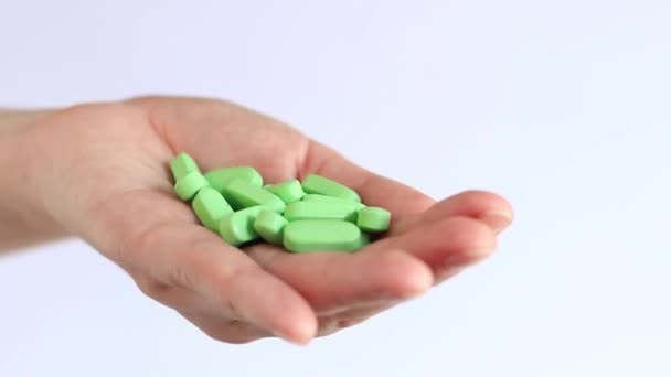 Vitamiineja naisen kädessä, vihreitä pillereitä. Ota yksi tabletti kouralliselta. Ravintolisät - Materiaali, video
