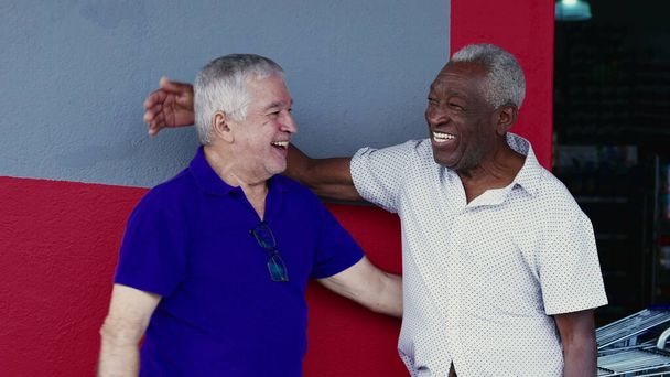 Authentic Interaction of Two Happy Diverse Older Friends, Hugging and Celebrating with High-Five, Standing Outside on Sidewalk (en inglés). Alegre compañía entre afroamericanos y caucásicos - Foto, Imagen