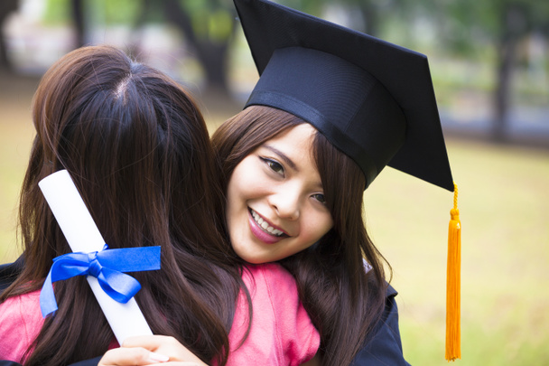 junge Absolventin umarmt ihren Freund bei der Abschlussfeier - Foto, Bild
