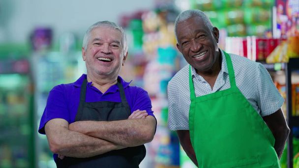 Улыбающиеся старшие работники в униформе продуктового магазина с радостным выражением лица - Фото, изображение