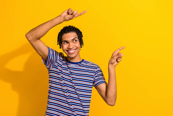 Portrait of optimistic man with piercing wear stylish t-shirt look directing at promo empty space isolated on yellow color background. - Fotó, kép