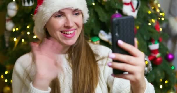Mujer joven llama a familiares o amigos a través de una videollamada, saludando y deseando Feliz Navidad o Feliz Año Nuevo. Imágenes de alta calidad 4k - Imágenes, Vídeo