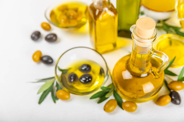 Olive oil in a bottle and gravy boat on the kitchen table. Oil bottle with branches and fruits of olives. Place for text. copy space. vegetable oil and salad dressing. - Photo, Image