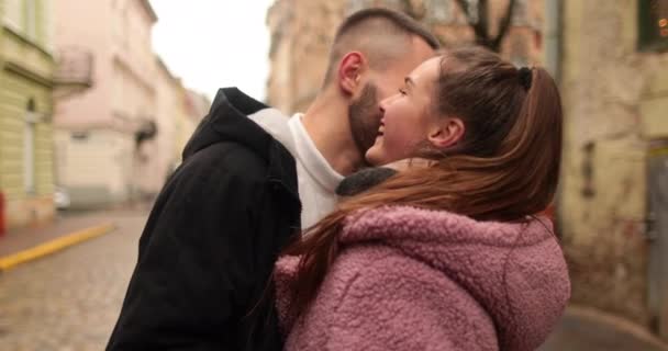 Kisses and hugs of a young couple in love. A romantic meeting of a young couple in the city center on a gloomy autumn day. Happy boy and girl hug, kiss, enjoying time together. - Footage, Video