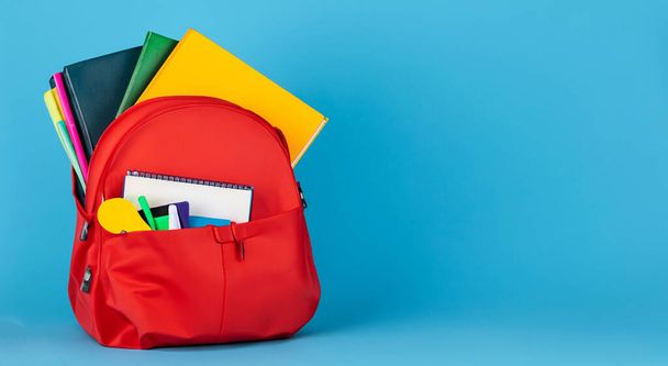 offene rote Tasche voller Schulbücher. zurück zum Schulkonzept auf blauem Hintergrund - Foto, Bild