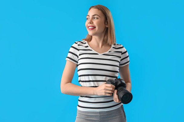 Fotógrafo femenino con cámara profesional sobre fondo azul - Foto, Imagen