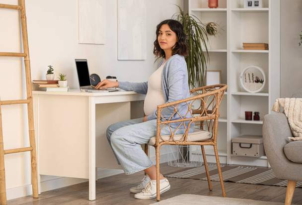 Jovem grávida trabalhando com laptop à mesa no escritório - Foto, Imagem